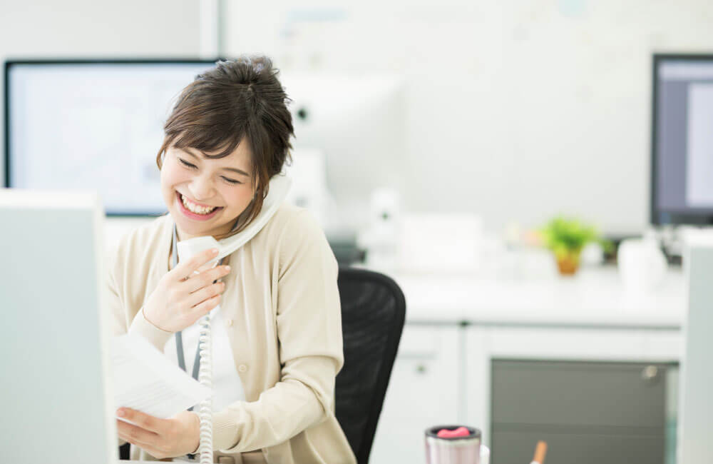 電話の受付応対をする笑顔の女性スタッフ